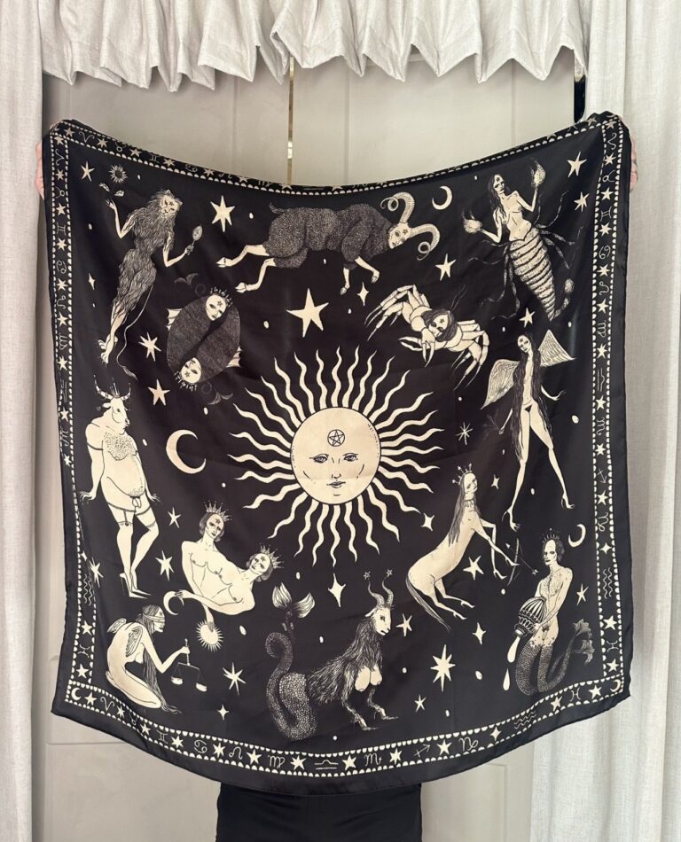 Black scarf with cream zodiac figures and stars around a cream sun