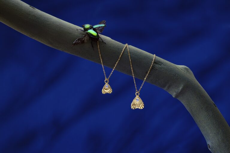 Jenni Stuart Fine Jewelry — two planchette necklaces and a green beetle on a branch