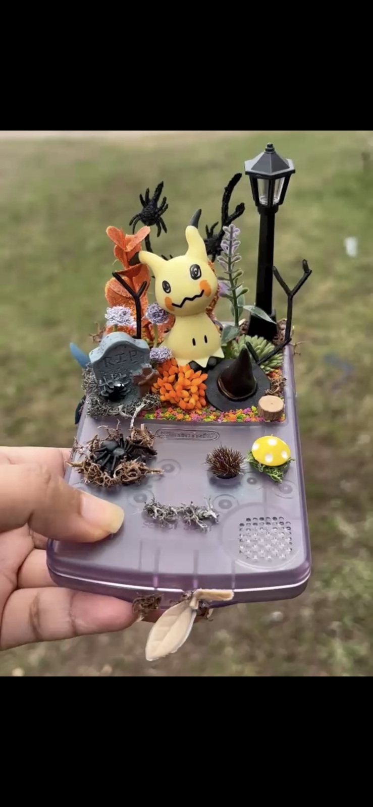Upcycled game-console case holding a spooky character scene and miniature lamp