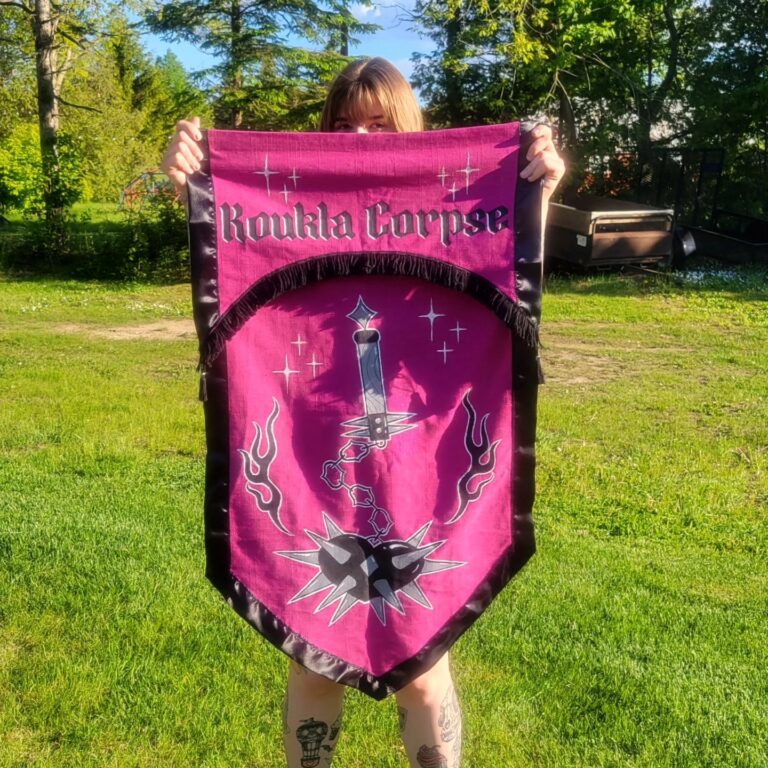 Artist holding a hand-painted Koukla Corpse banner